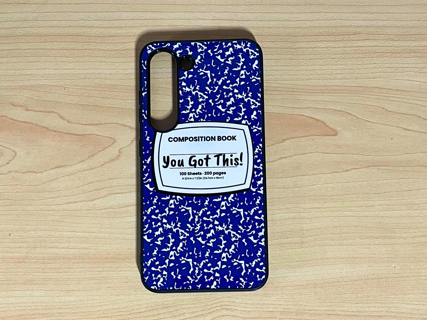 Samsung Galaxy case with blue and white composition notebook design and 'You Got This!' written in the middle displayed on a wooden surface.