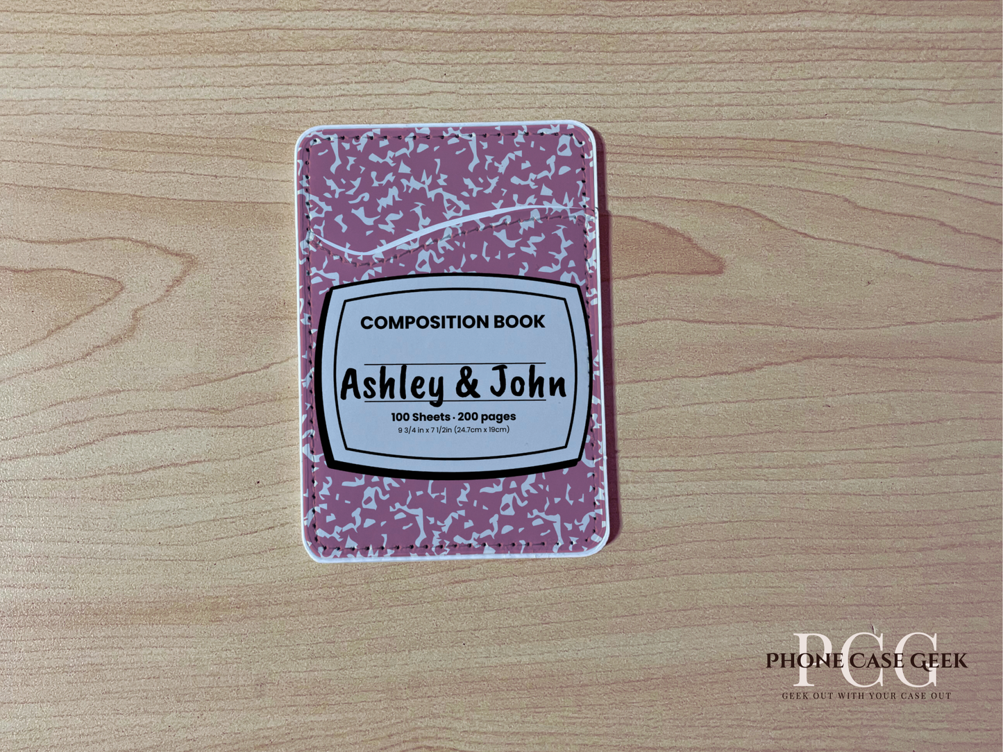 Custom adhesive phone wallet / card holder pink and white composition book with a "Ashley & John" text on a wooden surface.