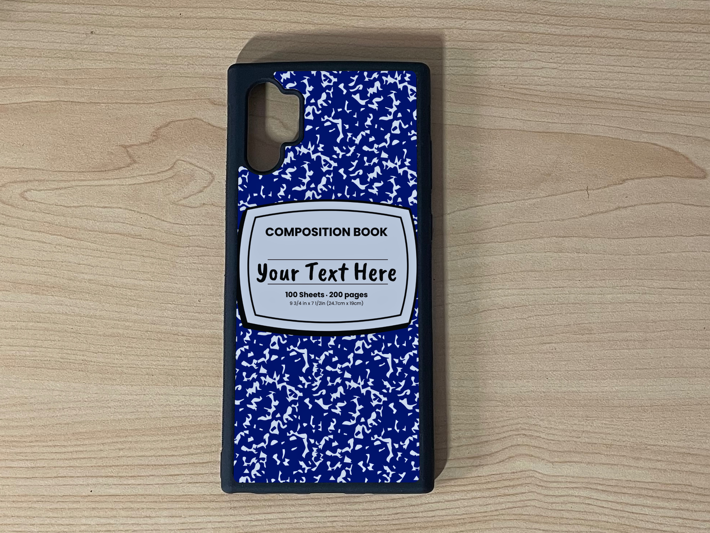 Custom phone case for the Samsung Note 10 Plus with a blue and white composition notebook design with text "Your text here" on a wooden surface.
