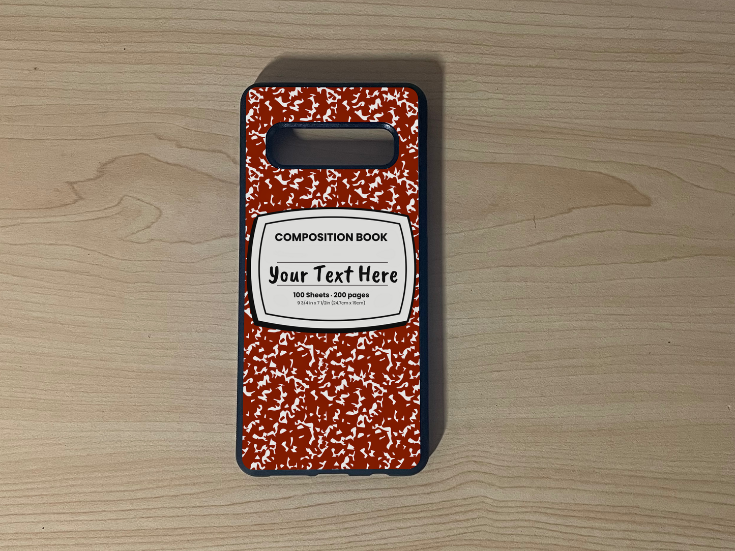 Custom phone case for the Samsung S10 and S10e with a red and white composition notebook design with text "Your text here" on a wooden surface.