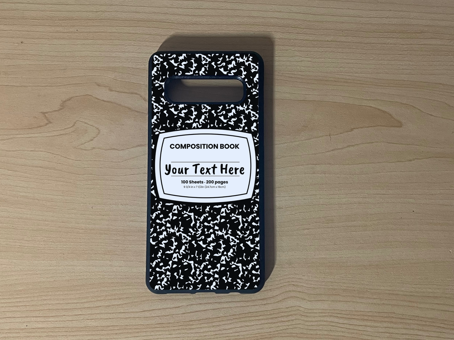 Custom phone case for the Samsung S10 and S10e with a black and white composition notebook design with text "Your text here" on a wooden surface.