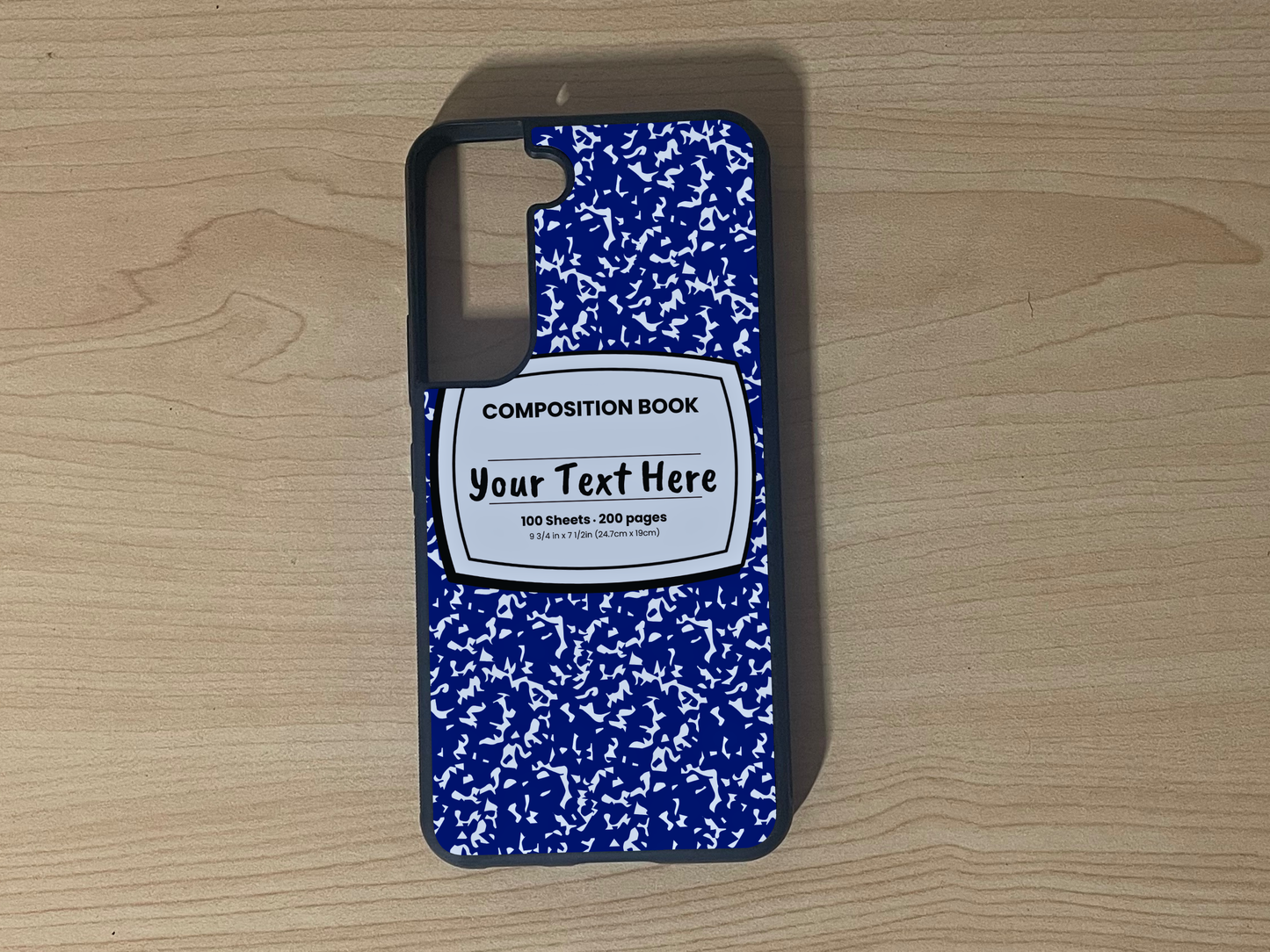 Custom phone case for the Samsung S21 and S21 Plus with a blue and white composition notebook design with text "Your text here" on a wooden surface.
