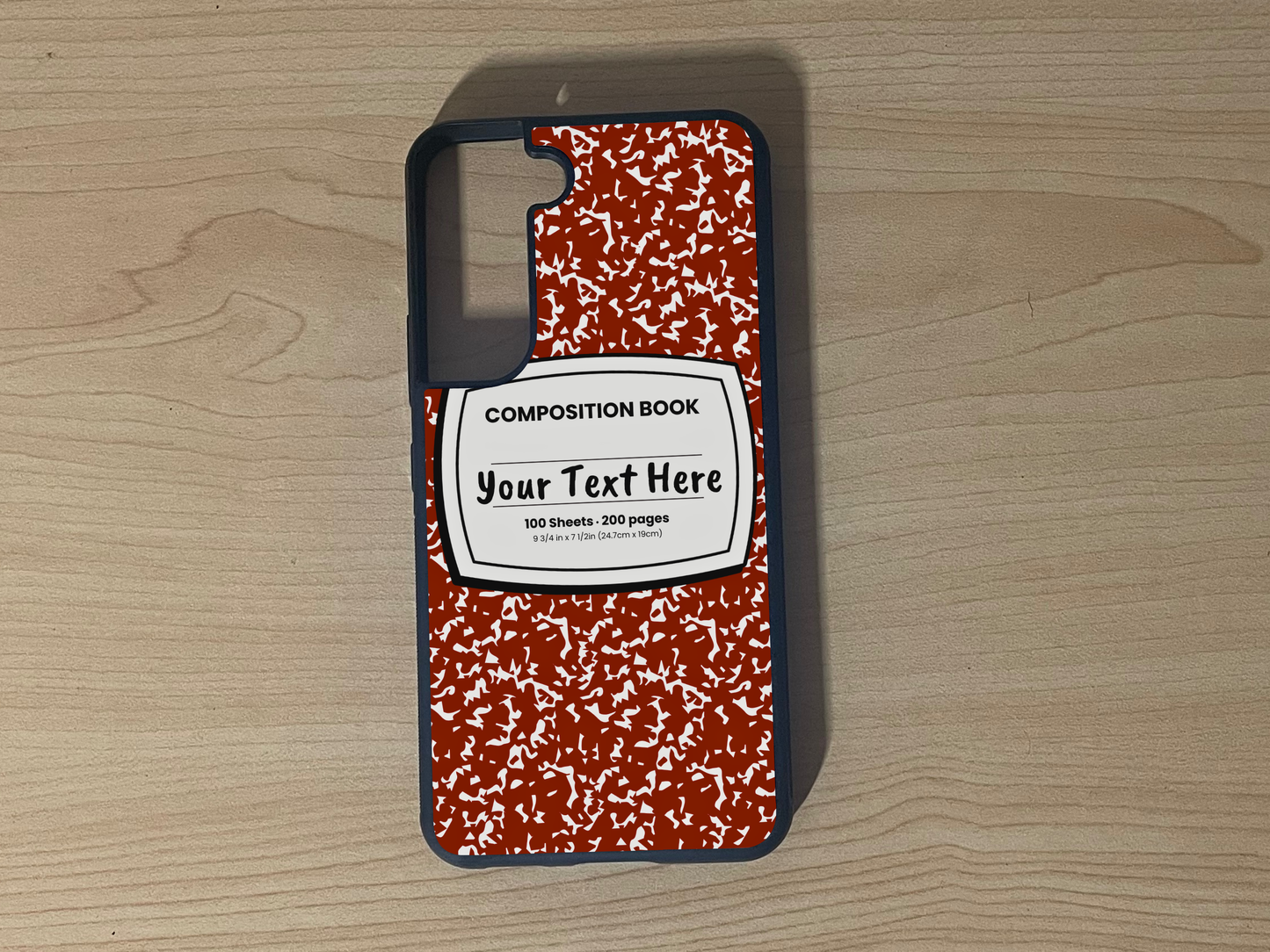 Custom phone case for the Samsung S21 and S21 Plus with a red and white composition notebook design with text "Your text here" on a wooden surface.