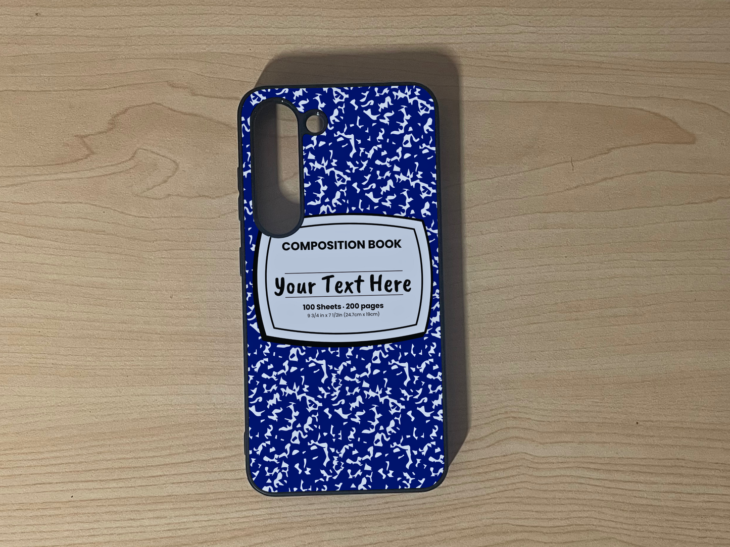 Custom phone case for the Samsung S23 and S23 Plus with a blue and white composition notebook design with text "Your text here" on a wooden surface.