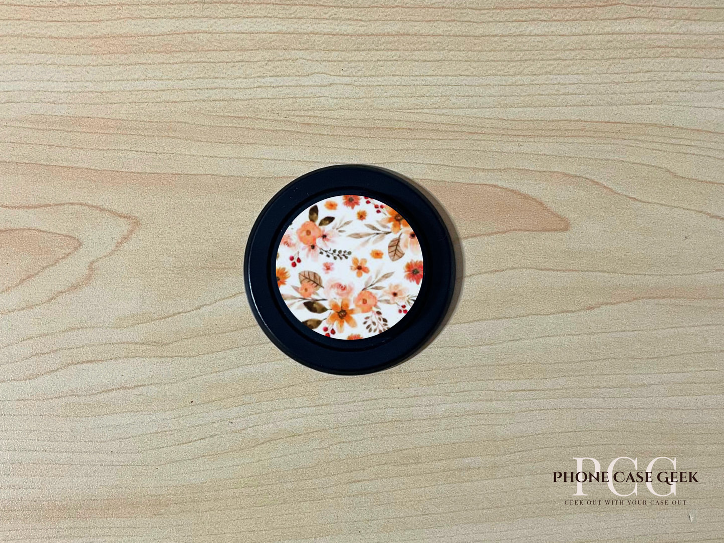 Black base custom Magsafe phone grip with floral design on a wooden surface