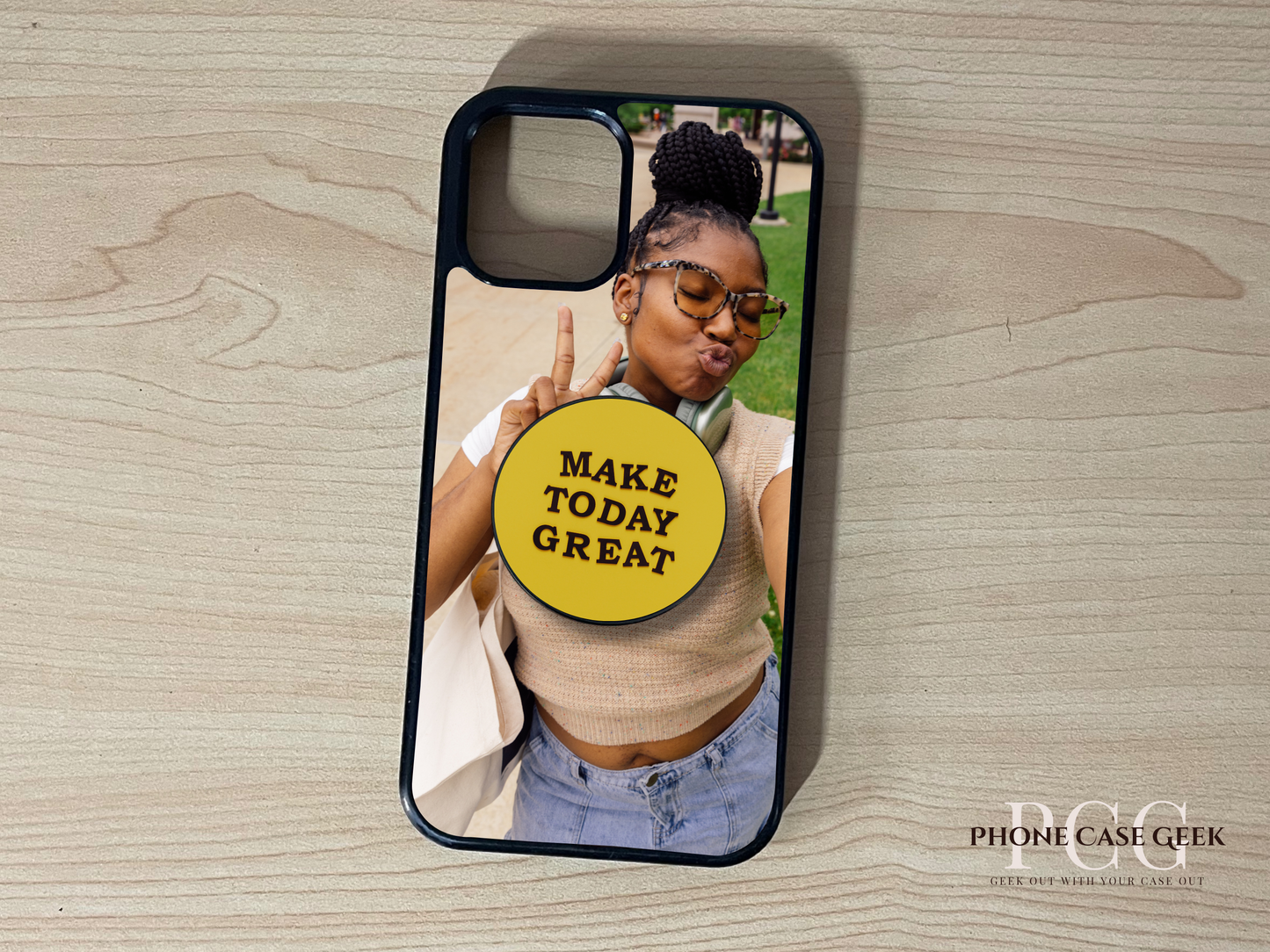 Custom iPhone case with a selfie of a woman and custom adhesive phone grip saying 'Make Today Great' on a wooden surface