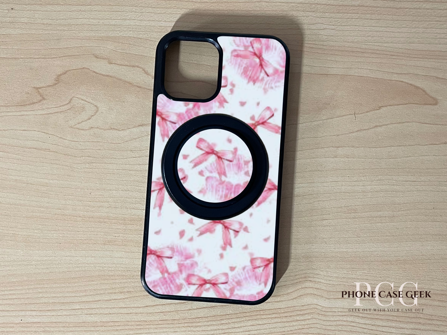 Custom Magsafe iPhone case with pink bows design with matching Magsafe phone grip on a wooden surface