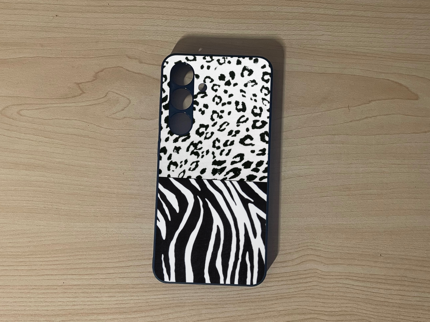 Custom phone case for the Samsung S24 and S24 Plus showing 2 photo collage with leopard and zebra pattern on a wooden surface