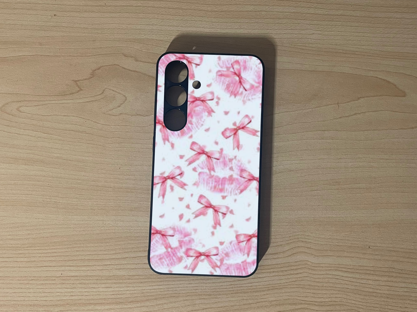 Custom phone case for the Samsung S24 and S24 Plus with pink bow pattern on a wooden surface