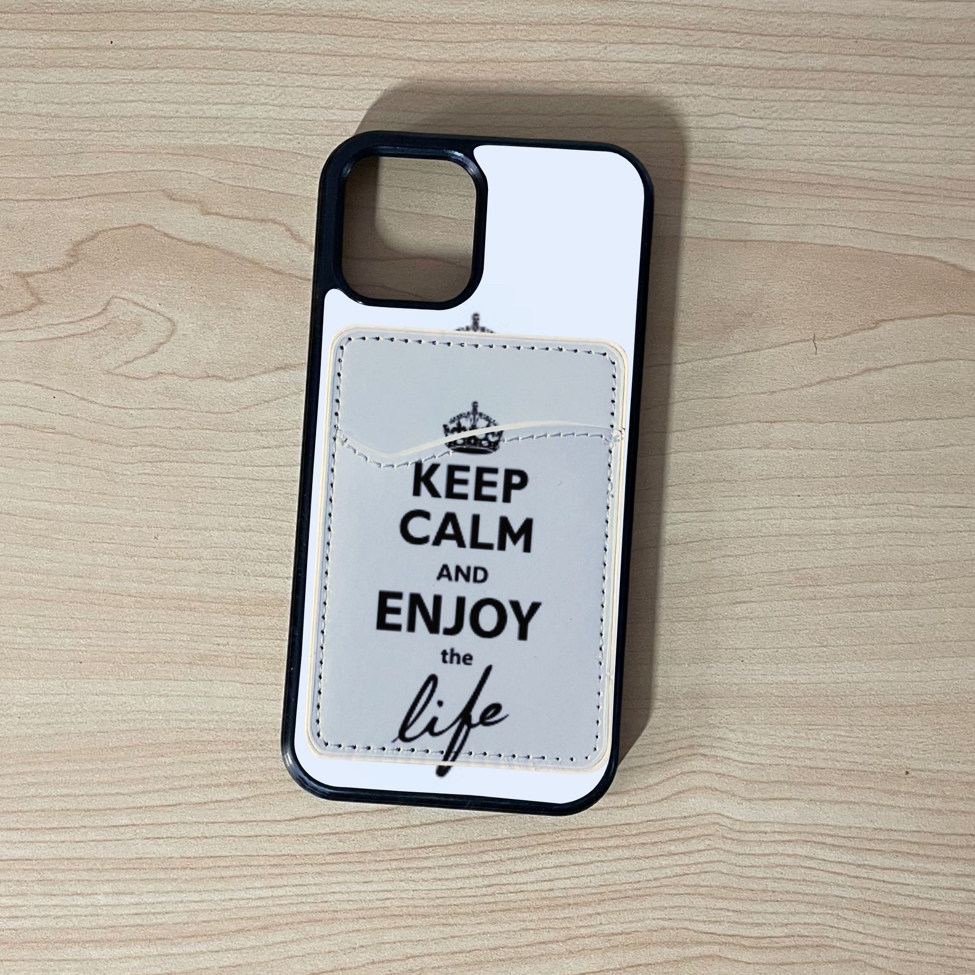 Custom phone case with 'Keep Calm and Enjoy the Life' text with matching phone wallet/card holder on a wooden surface.