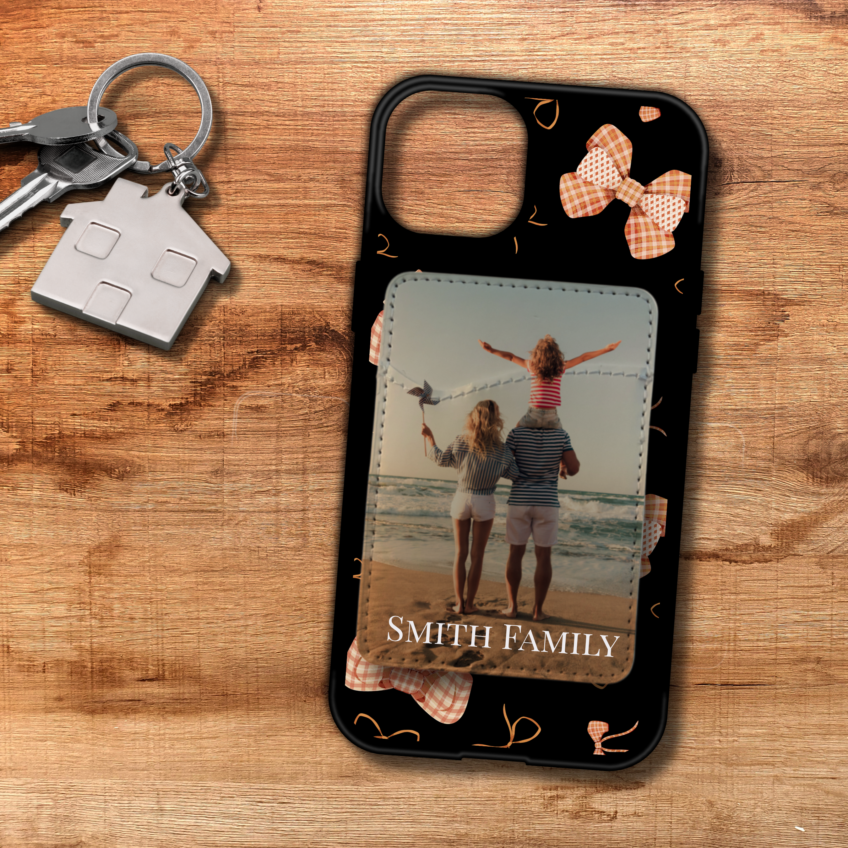 Custom phone case with a bow design on a sleek black background, featuring a personalized phone card holder attached to the back. The holder displays a vacation photo of a happy family with the text "Smith Family" printed below the image.