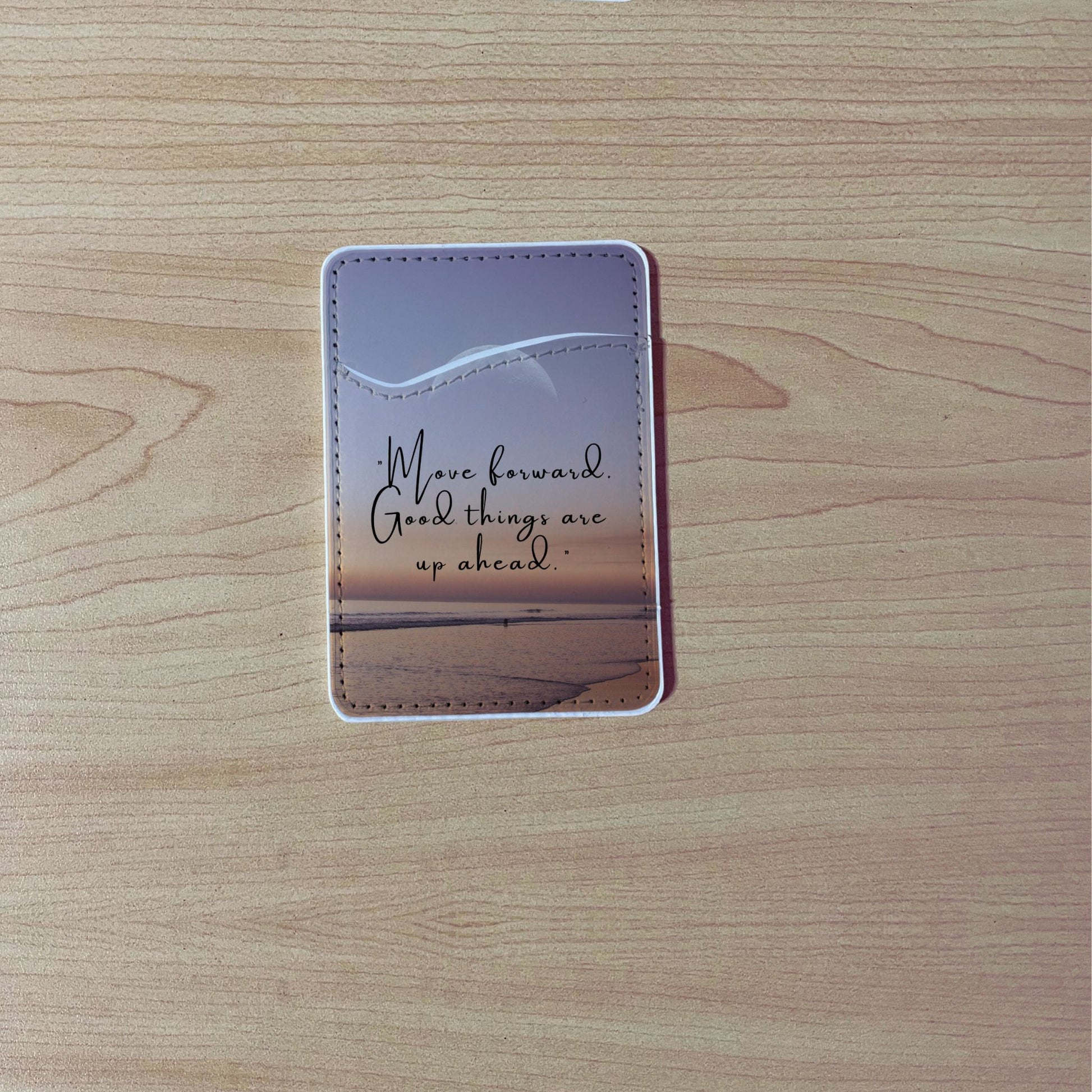 Custom phone wallet/card holder with beach image with quote design "Move forward good things are up ahead" text on a wooden surface.