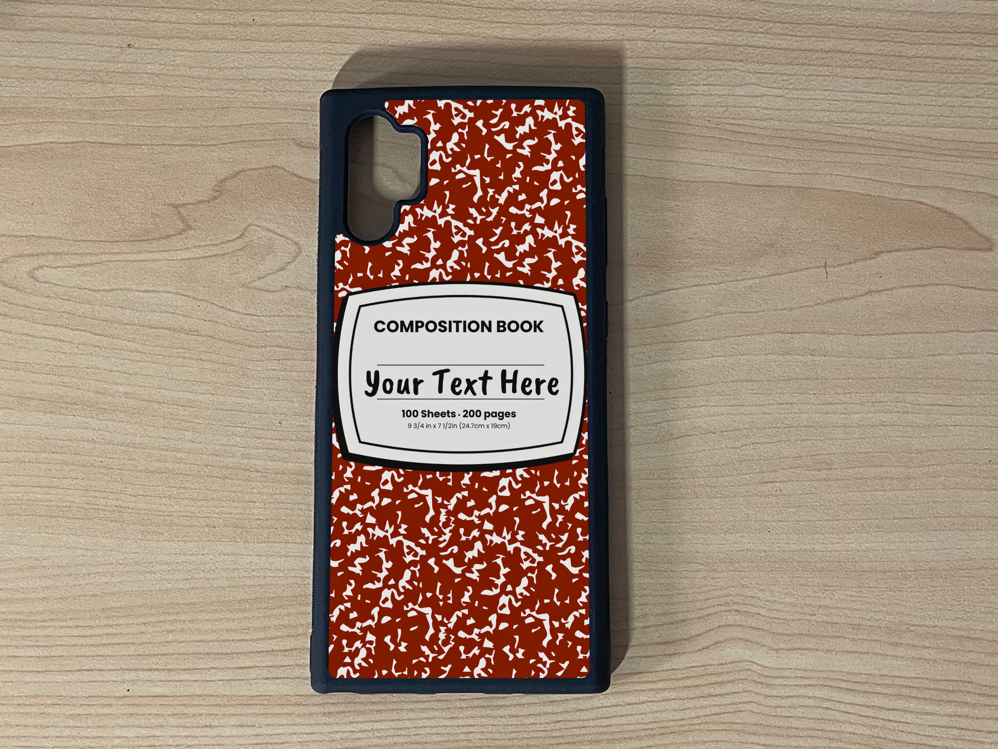 Custom phone case for the Samsung Note 10 Plus with a red and white composition notebook design with text "Your text here" on a wooden surface.