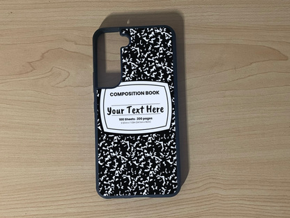 Custom phone case for the Samsung S21 and S21 Plus with a black and white composition notebook design with text "Your text here" on a wooden surface.