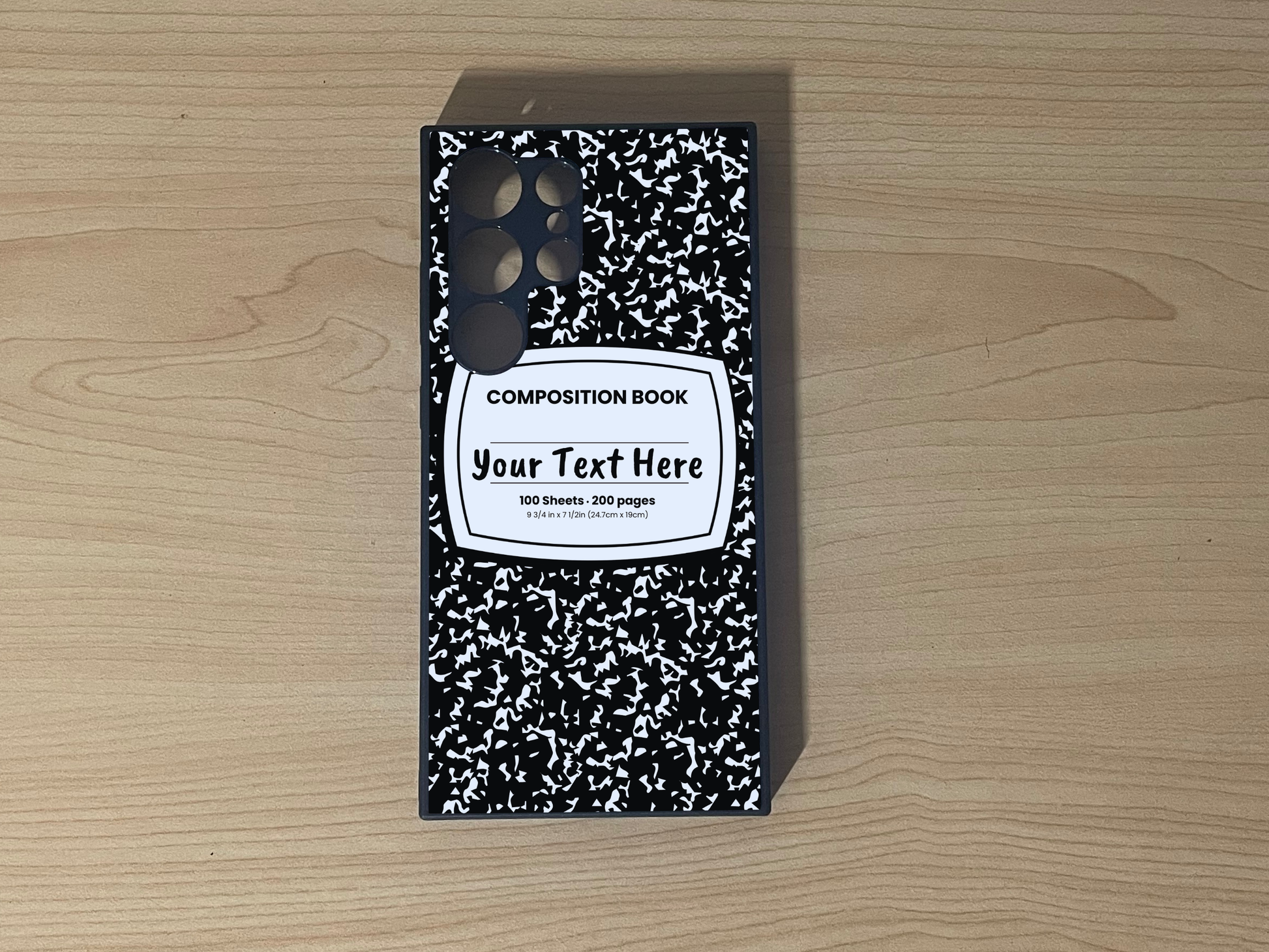 Custom phone case for the Samsung S24 Ultra, S23 Ultra, and S22. Ultra with a black and white composition notebook design with text "Your text here" on a wooden surface.