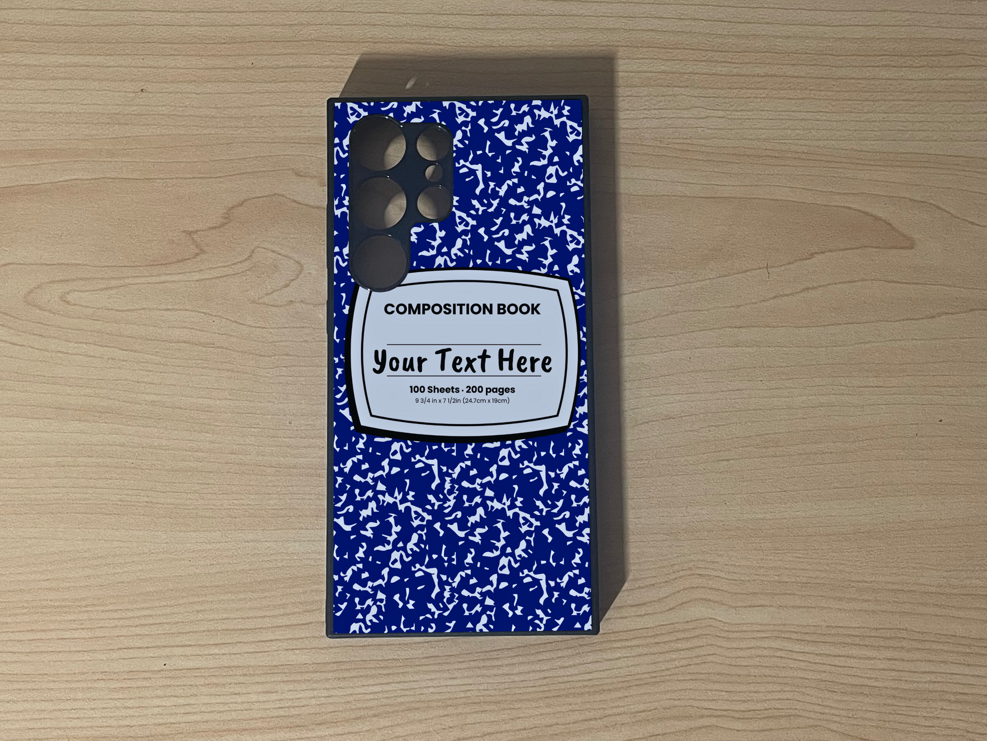 Custom phone case for the Samsung S24 Ultra, S23 Ultra, and S22 Ultra with a blue and white composition notebook design with text "Your text here" on a wooden surface.