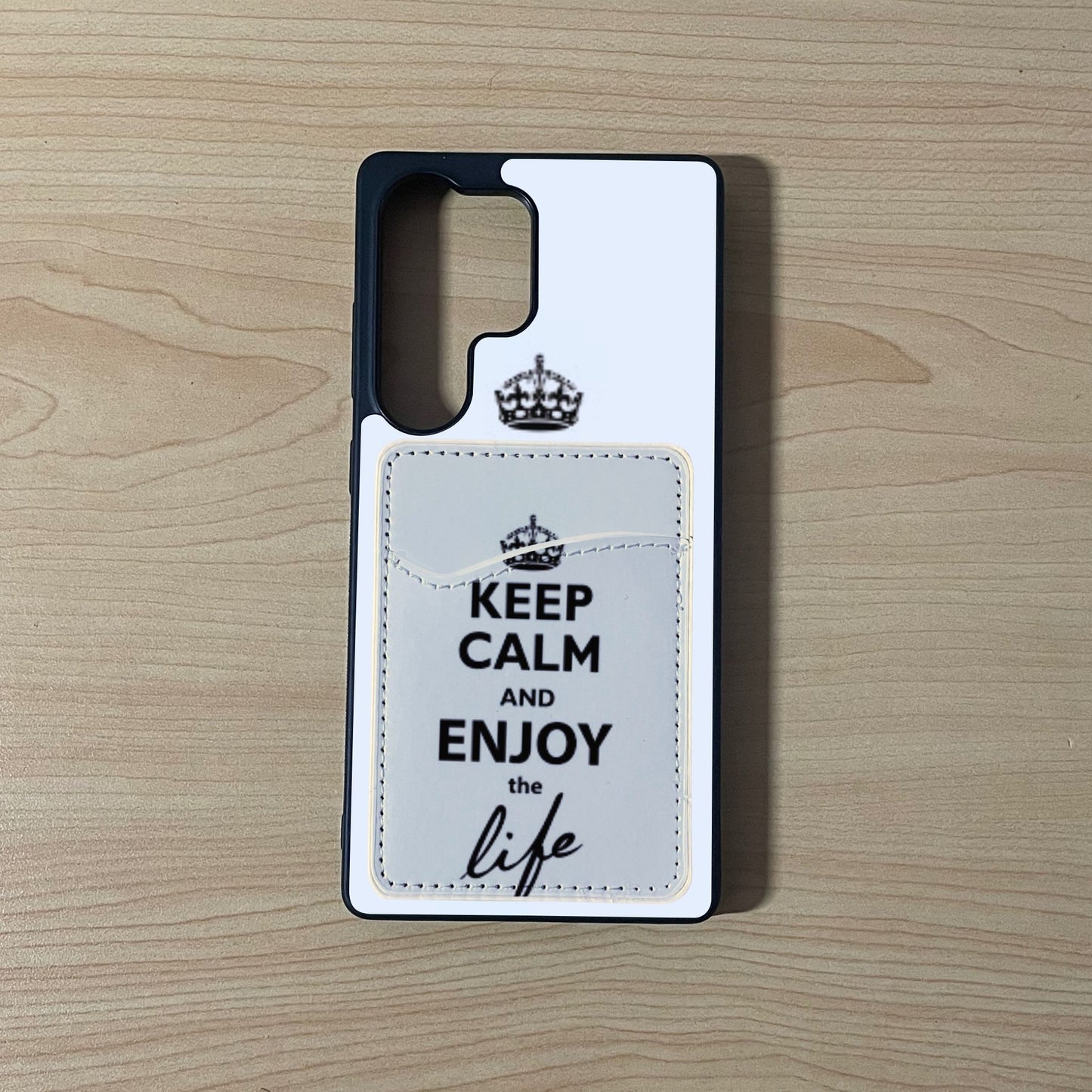 Custom phone case with 'Keep Calm and Enjoy the Life' text with matching phone wallet/card holder on a wooden surface