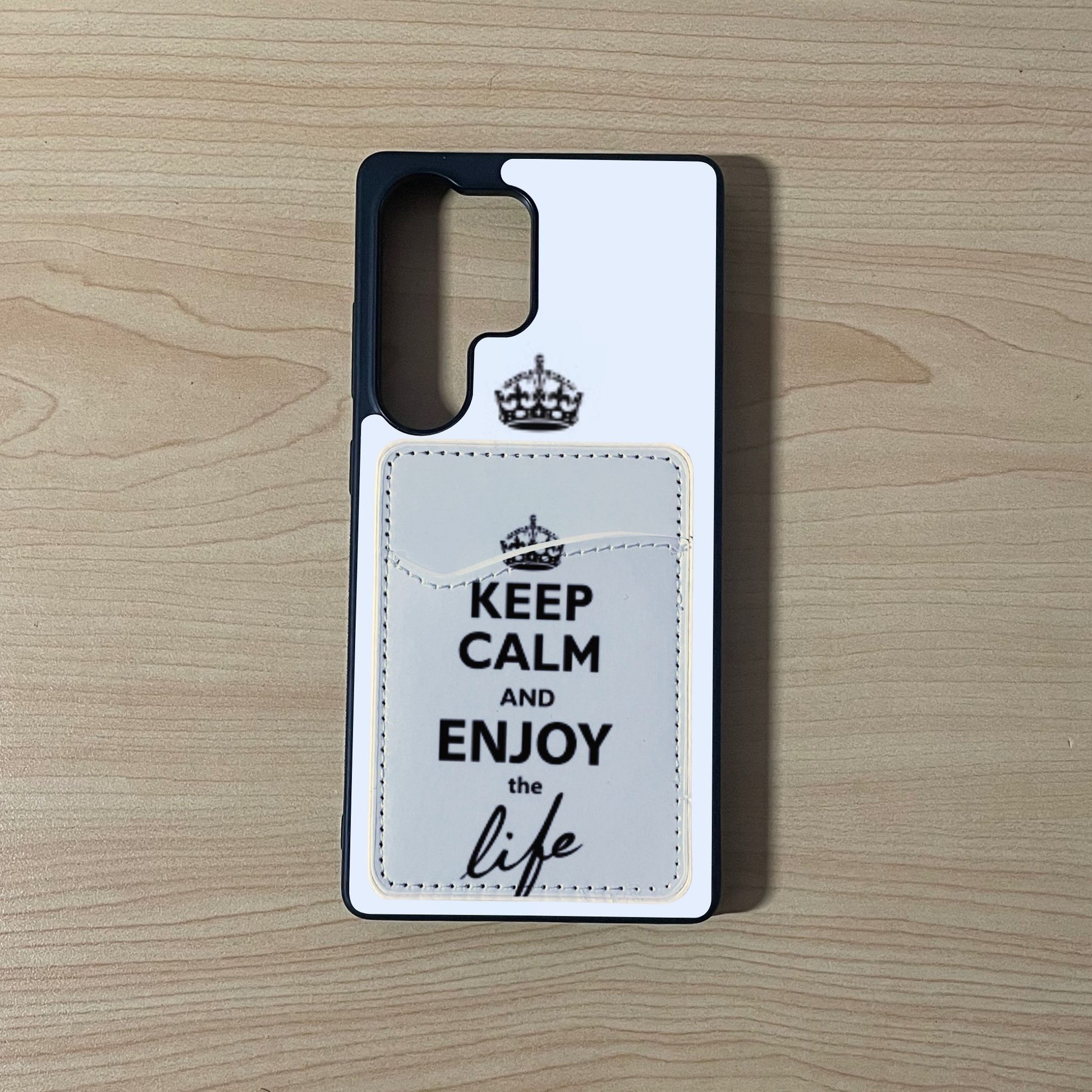 Custom phone case with 'Keep Calm and Enjoy the Life' text with matching phone wallet/card holder on a wooden surface