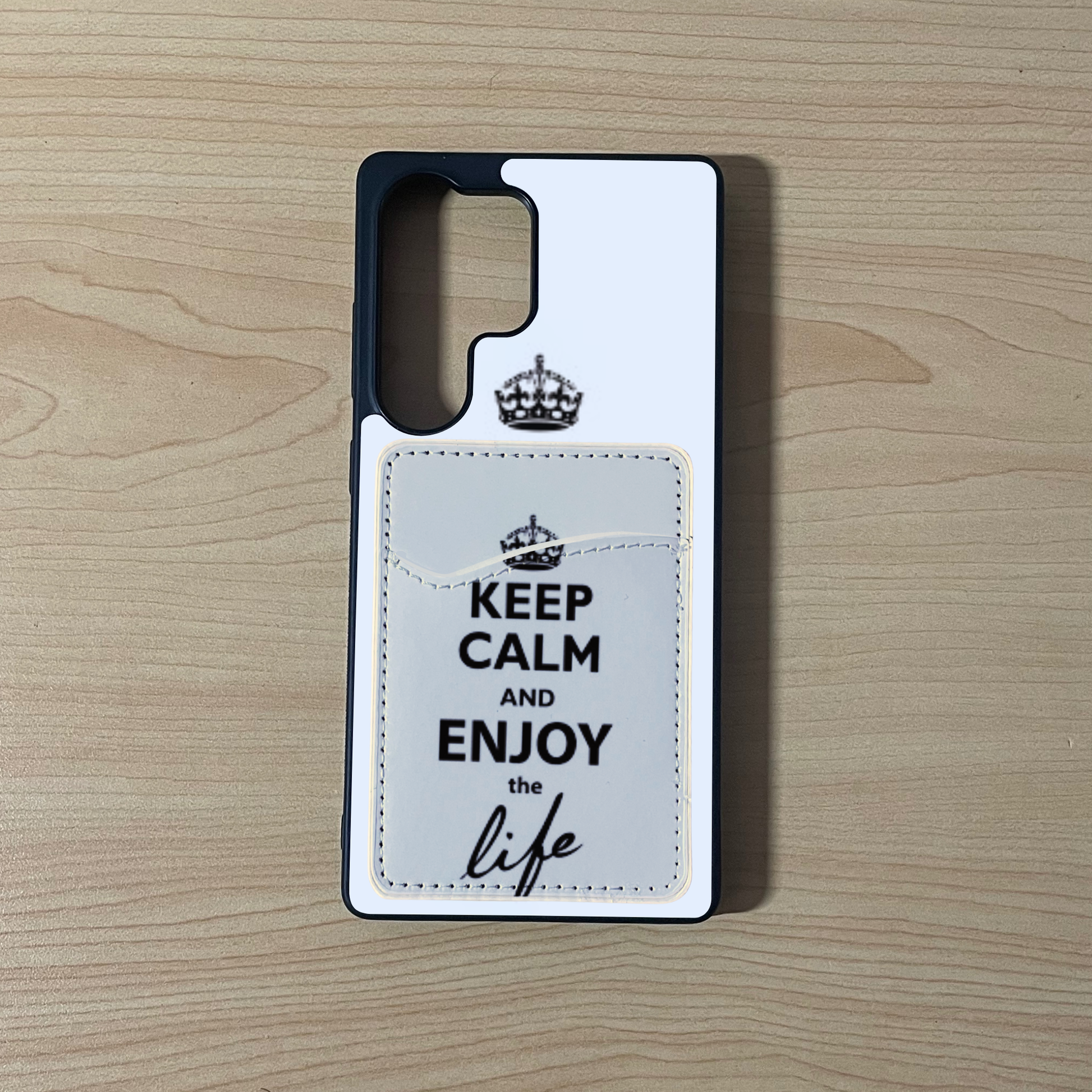 Custom phone case with 'Keep Calm and Enjoy the Life' text with matching phone wallet/card holder on a wooden surface