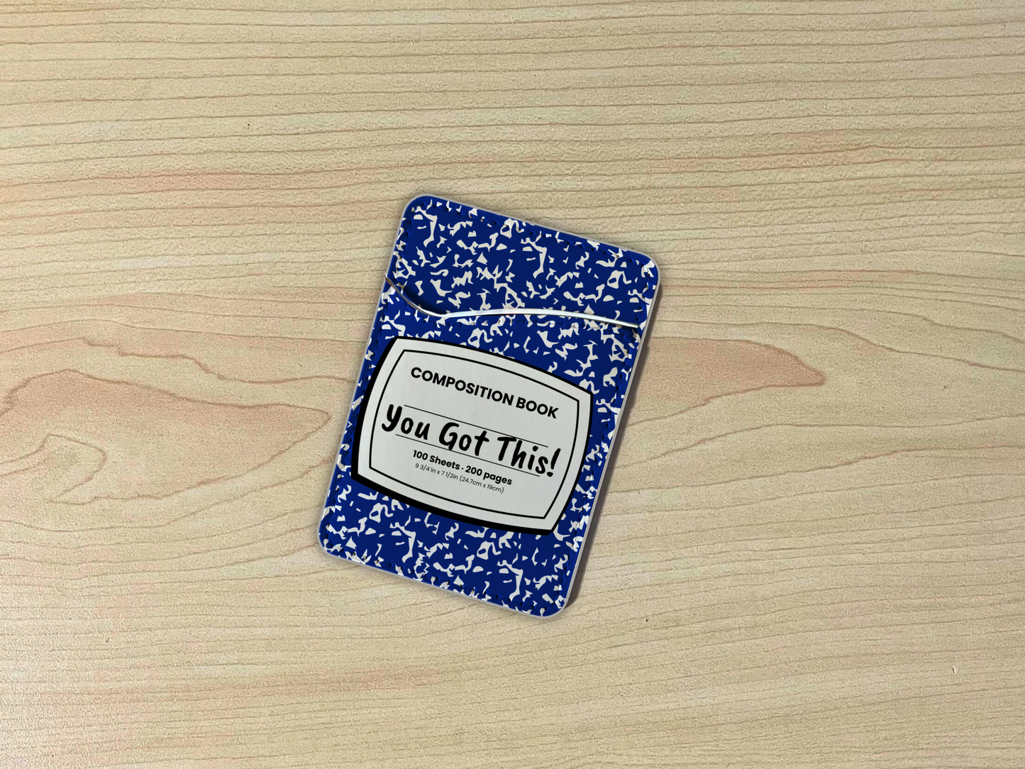 Blue and white composition notebook adhesive phone wallet/card holder with custom text "You Got This!" in the center on a wooden surface