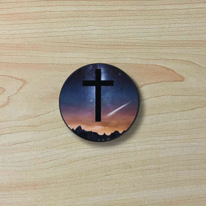 Custom adhesive phone grip with an image of a cross and the night sky on a wooden surface.