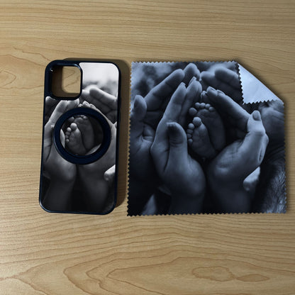 Custom MagSafe iPhone case bundle set with hands holding a baby's feet photo design with matching black phone grip and matching microfiber cloth phone screen cleaner on a wooden surface.