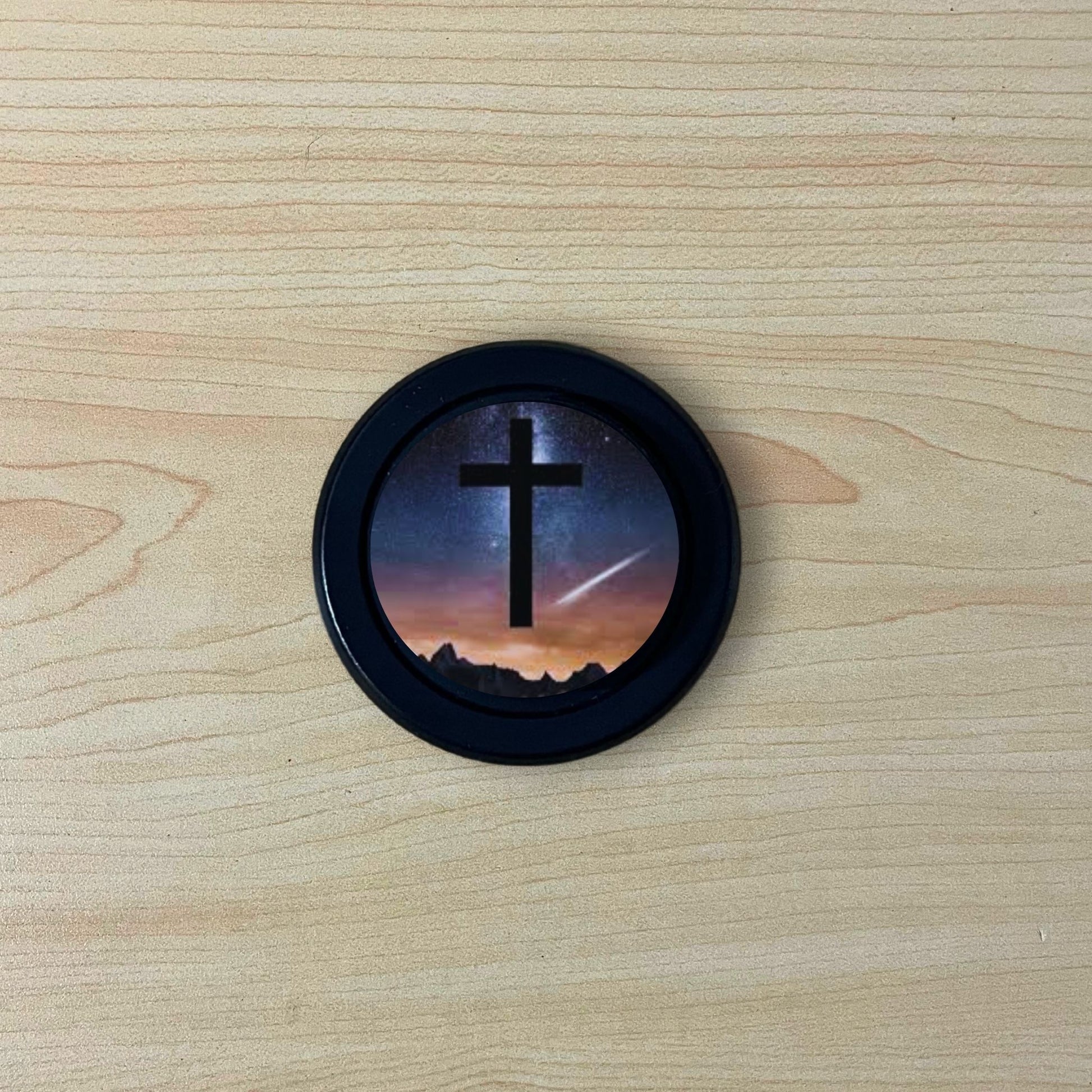 Custom magsafe phone grip with an image of a cross and the night sky on a wooden surface.