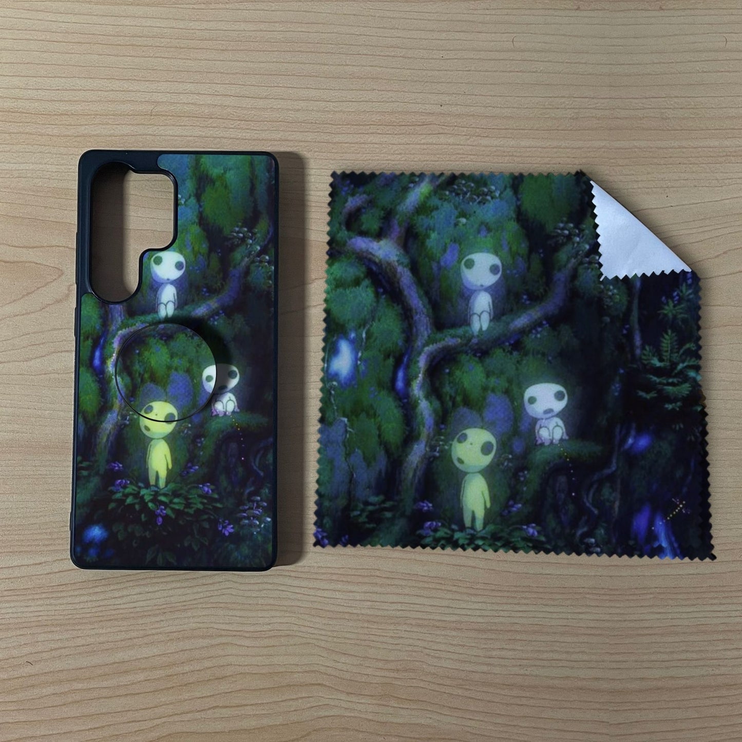 Custom Samsung case bundle set with a phone grip and cleaning cloth with matching forest design on a wooden surface.