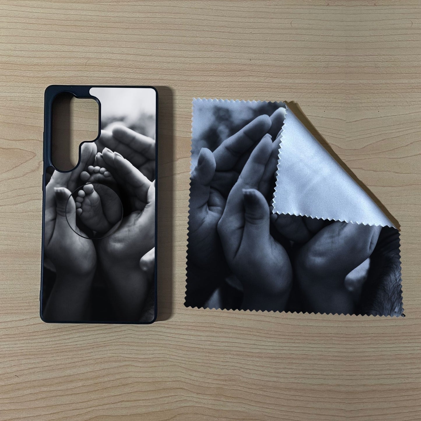 Custom Samsung case bundle set with hands holding a baby's foot design with matching phone grip and matching microfiber cloth phone screen cleaner on a wooden surface.
