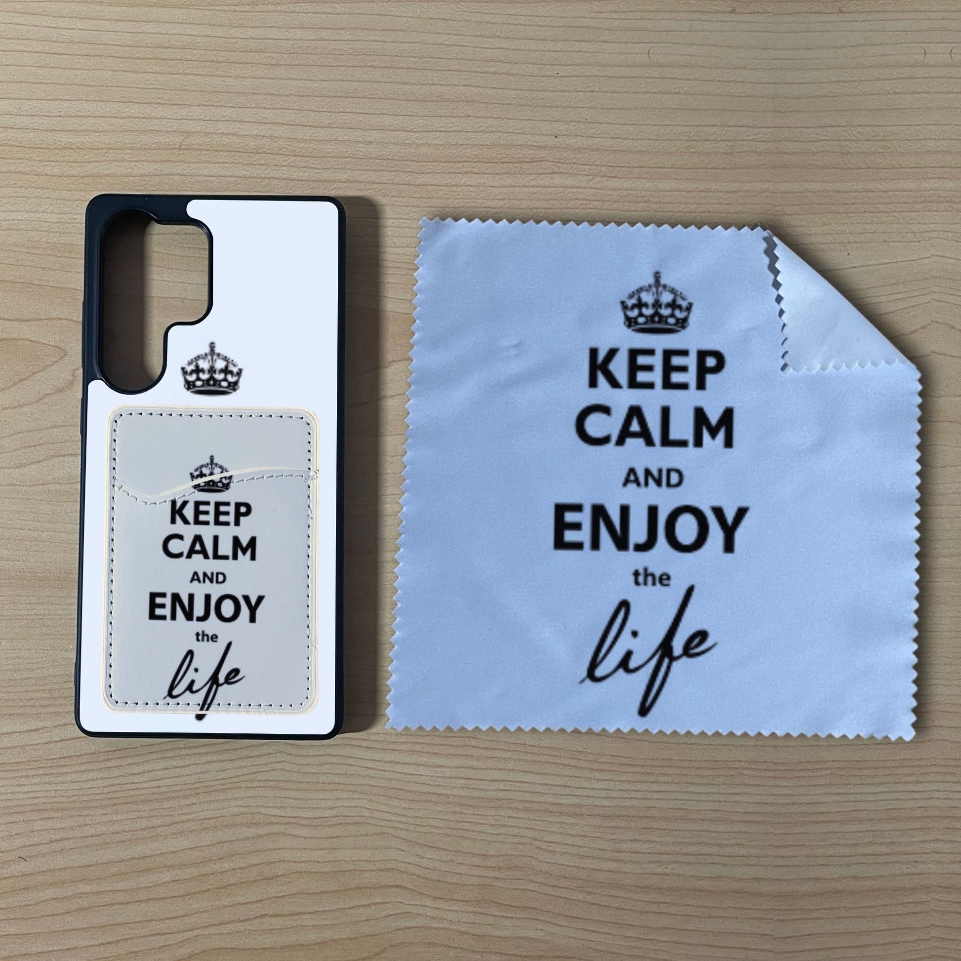Custom Samsung S25 Ultra case with text "Keep calm and enjoy the life" with matching phone wallet card holder and matching microfiber cloth phone screen cleaner on a wooden surface