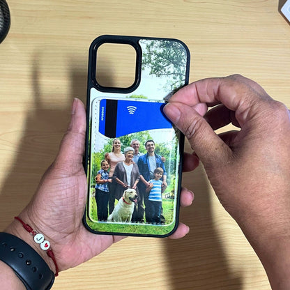 A person's hands holding a custom iPhone case with a custom printed design of a family and dog, featuring a matching card holder slot on the back, over a light wood desk.