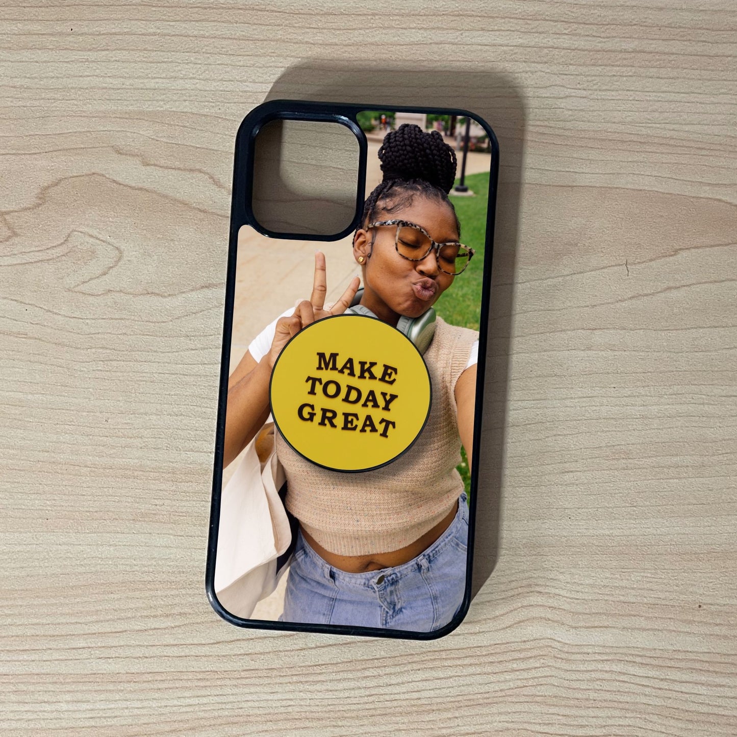 Custom iPhone case with a selfie of a woman and custom adhesive phone grip saying 'Make Today Great' on a wooden surface
