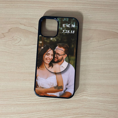 Custom iPhone case with photo of a couple and custom text initials on top with matching adhesive phone grip attached on a wooden surface. 