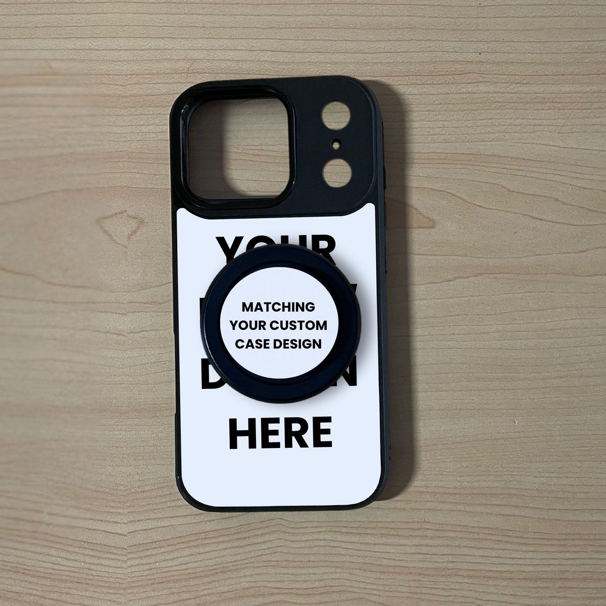 An iPhone 17 Pro/17 Pro Max case with a black bumper shown on a light wood grain background. A black MagSafe phone grip is attached in the center with text reading 'MATCHING YOUR CUSTOM CASE DESIGN'.
